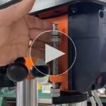 A twelve-inch benchtop drill press sits on a wooden workbench.